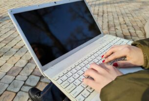 a woman is typing on her laptop outside